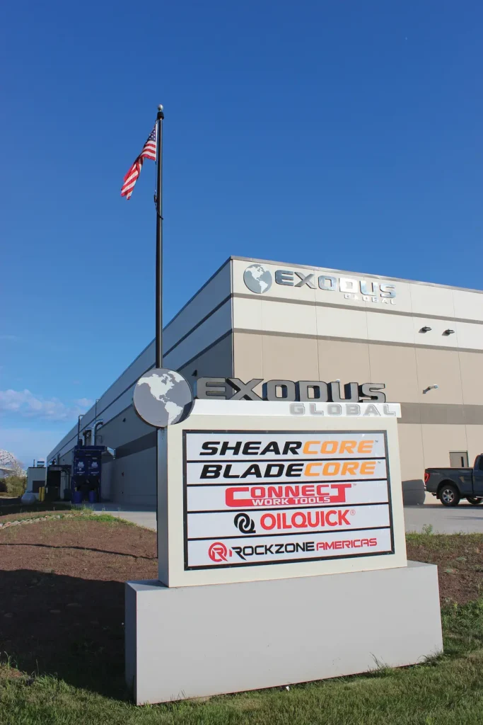 Exodus Global front sign with ShearCore, BladeCore, Connect Work Tools, OilQuick and Rockzone Americas listed. Exodus Global building and Flag in the background